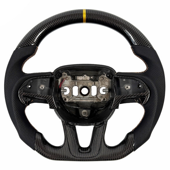 2015-2023 Dodge Charger and Challenger carbon fiber steering wheel by Texas Carbon, shown from the front with a gloss woven finish, black perforated leather grips, gold stitching, a gold 12 o'clock center stripe, matching carbon fiber button trim and lower-spoke trim, a round top and flat bottom, and an exposed airbag mounting hub.