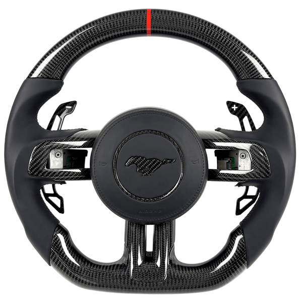 2015–2023 Ford Mustang S550 carbon fiber steering wheel by Texas Carbon with gloss woven carbon fiber, black leather grips, paddle shifters, a flat-bottom rim, and a red center stripe.