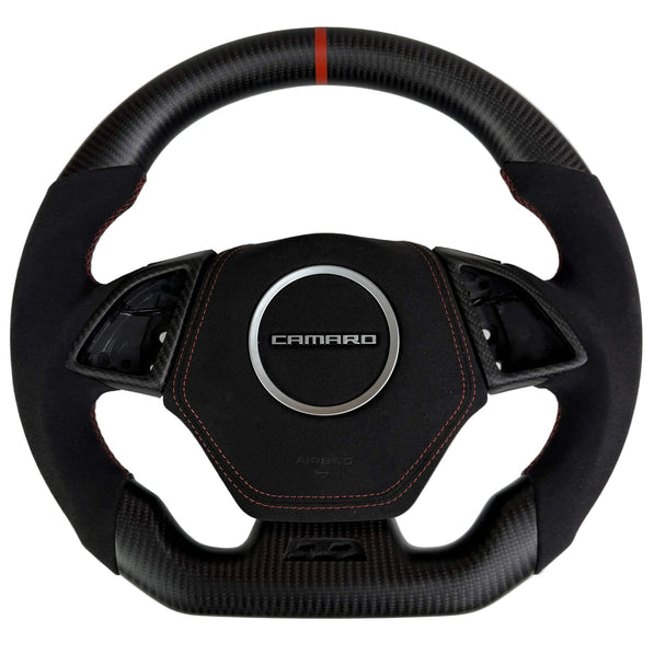 Front view of a 2016–2024 Chevrolet Camaro flat-bottom carbon fiber steering wheel with black Alcantara grips, orange stitching, and an orange center stripe.